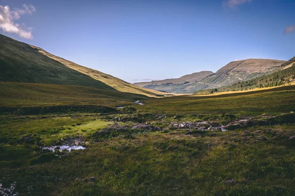緑の丘や土地の真ん中に小さな滝があるスコットランド スカイ島の風景の広い水平方向のショット — ストック写真