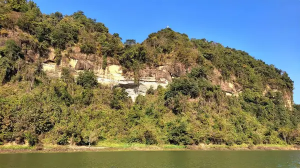 青い空を背景に湖の岸に木で覆われた岩の美しい景色 — ストック写真