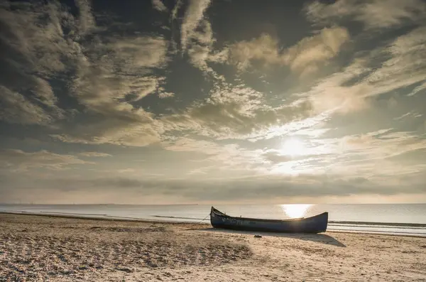 曇った空に対して海によってビーチで放棄されたボート — ストック写真