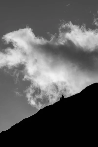 Bir Dağın Yamacında Dramatik Bir Gökyüzüne Karşı Oturan Bir Insanın — Stok fotoğraf
