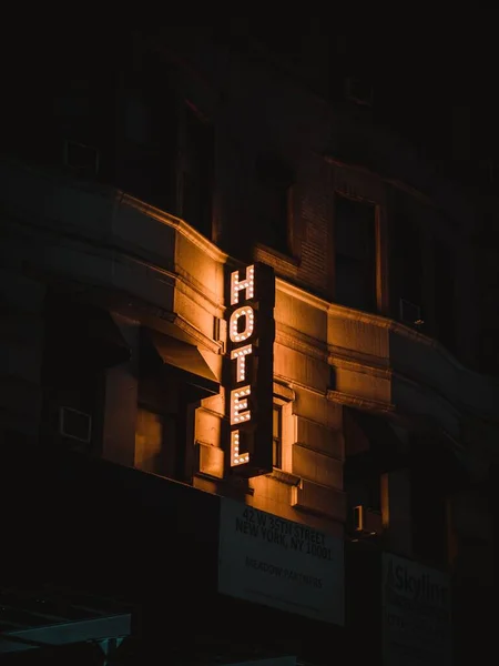 从建筑物上吊下来的亮着灯的酒店告示牌的垂直照片 — 图库照片