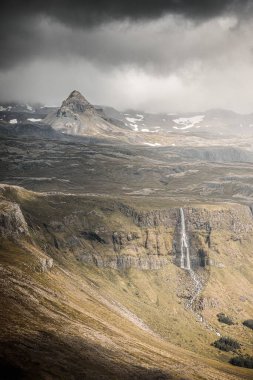 Bulutlu bir günde Bjarnafoss şelalesinin İzlanda 'daki uçurumdan düşüşünün dikey görüntüsü.