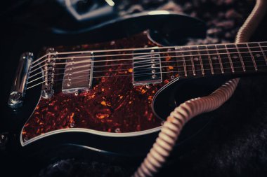 Yerdeki modern, kahverengi elektro gitarın yakın plan çekimi.