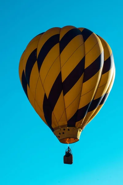 一个美丽的黄色和蓝色热气球在蓝天的映衬下高高地飞行 — 图库照片