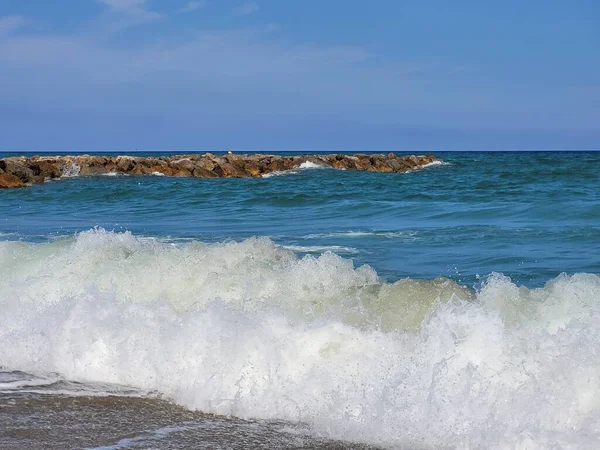波のビーチからの美しいショットと背後にある石の壁 — ストック写真