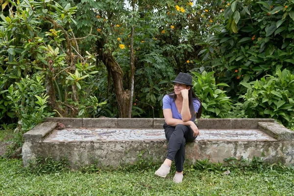 Krásná Latinskoamerická Žena Odpočívající Kamenné Lavičce Zahradě Obklopené Zelenými Stromy — Stock fotografie