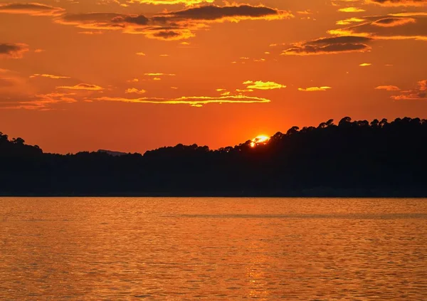 オレンジ色の空に美しい黄金の雲の裏地と強い夕日の絵のような景色 — ストック写真