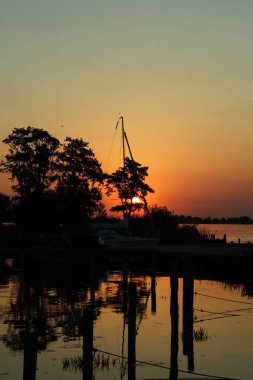 Sahilde gün batımında arka plan ve duvar kağıtları için mükemmel bir teknenin dikey çekimi.