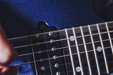 Gitar tellerinin yakın plan çekimi bir gitar penası tarafından seçilir.