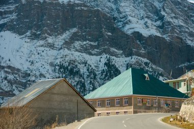 Dağlarda kar ve ağaçlar mavi gökyüzü ve bulutlar bir arka plan üzerinde yolun kenarında kaplı asfalt yoldan doğal kış görünümü