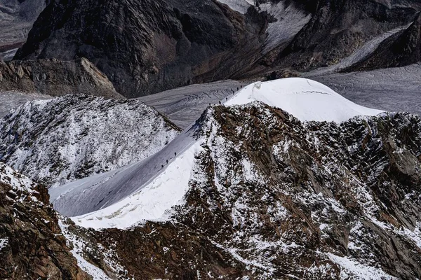日の出の直線で雪に覆われた山に登るハイカーの高い角度のショット — ストック写真