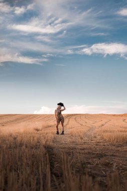 Açık alanda poz veren beyaz bir kadının dikey çekimi.