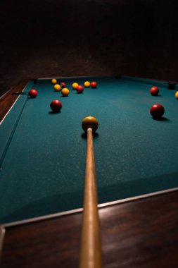 Bir bilardo masasının dikey görüntüsü. Toplar ve işaret karanlık bir odada.