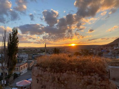 Türkiye 'nin Kapadokya kentinin geleneksel evleri üzerinde dramatik bir gün batımı manzarası