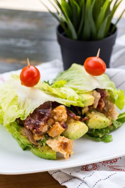 Bir tabak et ve marulla sarılmış avokado.