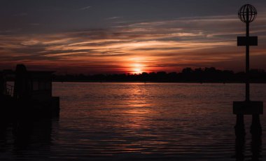 Venedik, İtalya 'da sakin bir gölün üzerinde renkli bulutlu bir gökyüzü ile güzel bir gün batımı manzarası.