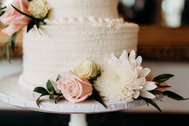 Düğün töreni için hazırlanmış çiçeklerle süslenmiş güzel beyaz düğün pastası.