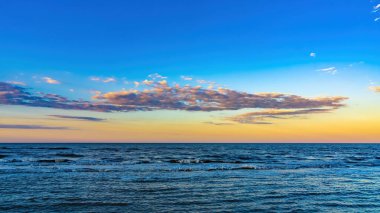 Güzel mavi bir denizin üzerinde parlak bir günbatımı gökyüzü