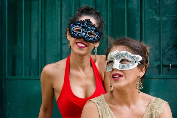 两名身着浅色夏装 戴着狂欢节面具的女性与一扇门相映成趣 — 图库照片