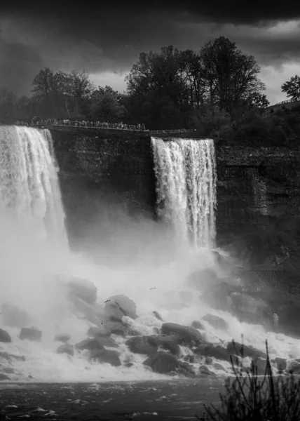 一道白色泡沫状瀑布从岩石山中流下的垂直灰度镜头 — 图库照片