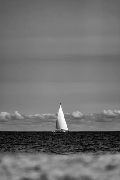Vertikal Gråskala Skott Segelbåt Havet Mot Molnig Himmel — Stockfoto