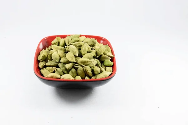 一堆堆绿色的豆蔻在一个被白色背景隔开的碗里 — 图库照片