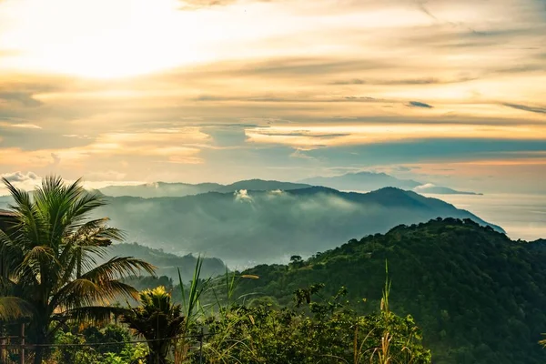 stock image An aerial view of mountains covered in forests at sunset with a dramatic sky in the background