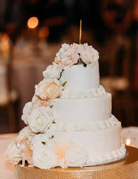 白色玫瑰覆盖的三层婚礼蛋糕的精选焦点 蛋糕侧面有一个狗的雕像 — 图库照片
