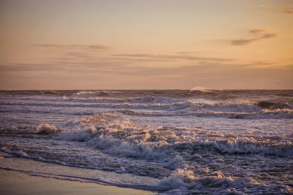 オレンジ色の夕日の間に小さな波がある海の美しい景色 — ストック写真