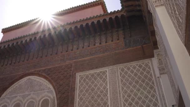 モロッコのマラケシュにあるMadrasa Ben Youssefビルの後ろに輝く明るい太陽の低角度ショット — ストック動画