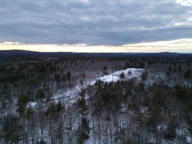 Karlı bir ormanın üzerinde, gecenin bulutlu gökyüzünün altında bir dron vurdu.