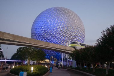 A spaceship Earth in Epcot with Monorail train during sunset clipart