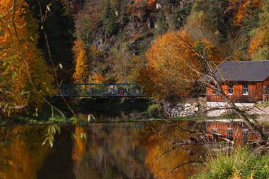 Güzel bir sonbahar gününde bir gölün kıyısındaki eski bina ve köprü.