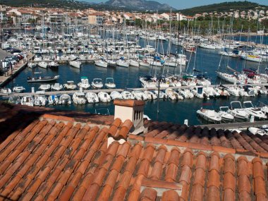 Arka planda rıhtımdaki tekne ve dağlarla dolu bir limanın tepesinden bir manzara.