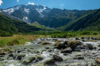 Tour Du Mount Blanc 'ta yeşil bir manzaranın ortasında akan bir nehrin nefes kesici görüntüsü.