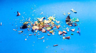 Mavi arka planda izole edilmiş renkli kalem kalıntılarının yakın çekimi