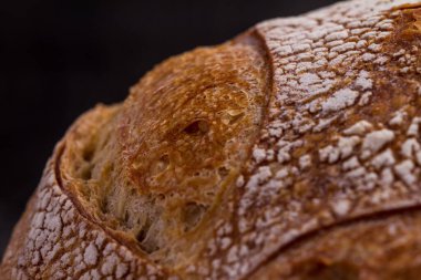 Koyu arkaplanda yuvarlak bir ekmeğin makro çekimi.