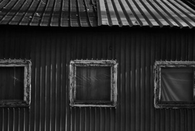 Pencereleri plastik poşetlerle kaplı eski bir kırsal evin gri pulu.