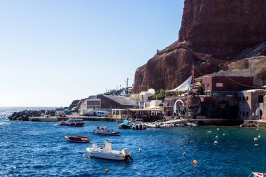 Dağ yamacında bir sahil, kayık ve şamandıralarla dolu berrak bir denizi geçti..