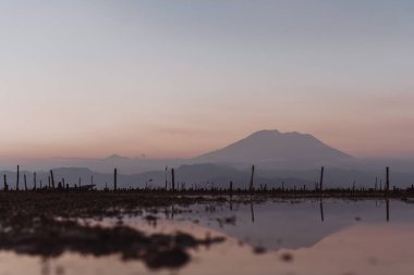Nusa Lembongan, Endonezya 'da gün batımında bir dağı yansıtan bir su birikintisi manzarası