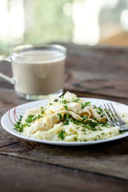 Beyaz bir tabakta servis edilen ve arka planda içki olan dikey yakın plan makarna.