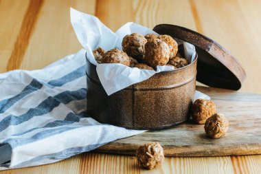 Yulaf ezmeli kurabiye, tahtadan bir tahta ve çizgili bir kumaş üzerinde kahverengi bir kutuyu ısırır.