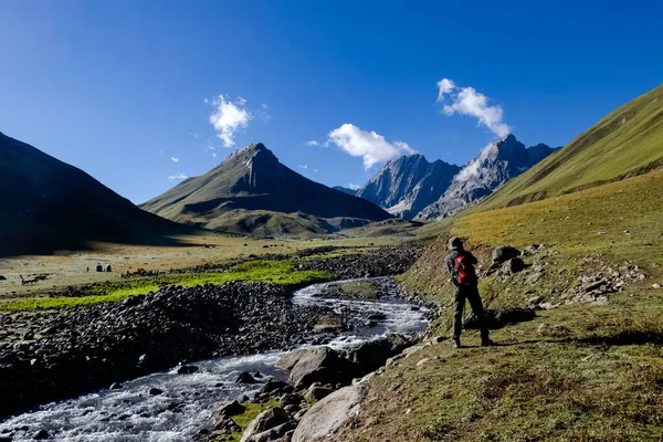 Een Man Rotsachtige Bergen Bedekt Met Groen Gras Een Rivier — Stockfoto