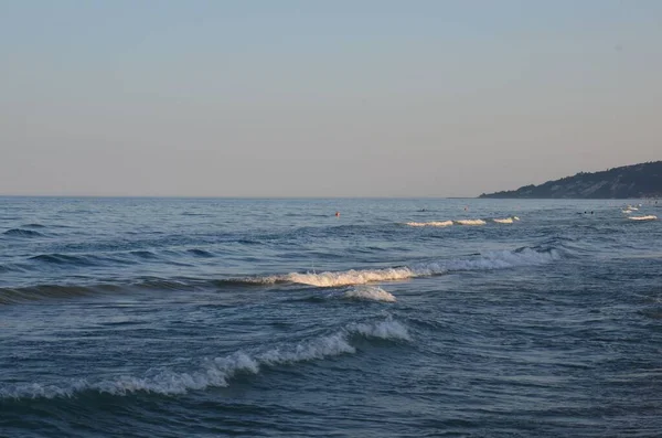 Pembe Gökyüzünün Altındaki Tepelerle Çevrili Mavi Deniz Dalgalarının Güzel Bir — Stok fotoğraf