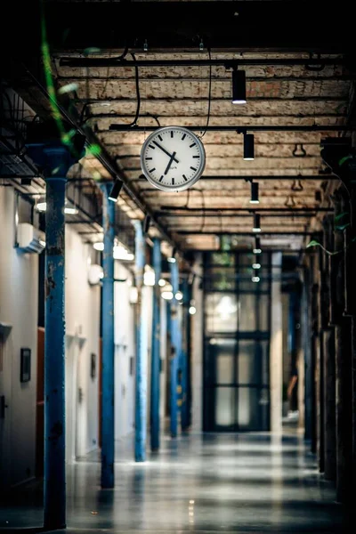 空荡荡的建筑物里挂着一个钟的垂直镜头 — 图库照片