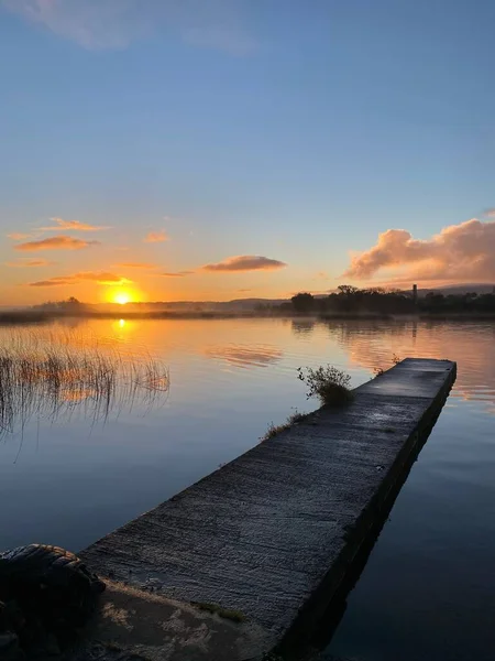 日落时在宁静的湖面上一个木制码头的垂直拍 — 图库照片
