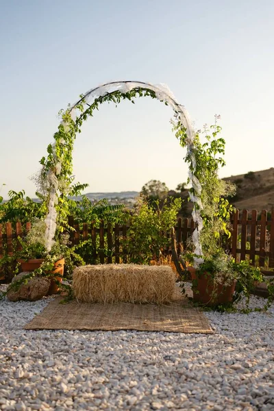 葉で装飾された結婚式のアーチの垂直映像 中央にわらの束 自然に囲まれて — ストック写真