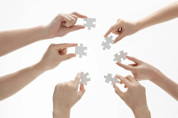 Eine Nahaufnahme Von Händen Die Puzzleteile Vor Weißem Hintergrund Halten — Stockfoto