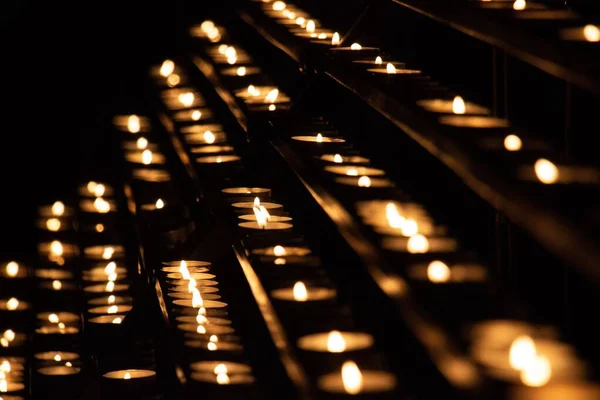 在教堂黑暗的背景上一排排点燃的蜡烛的特写 — 图库照片