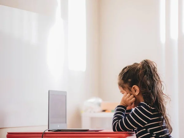 Een Kleuterschoolmeisje Aan Het Bureau Ongeïnteresseerd Kijkend Naar Een Laptop — Stockfoto